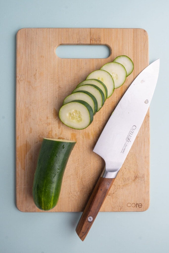 Half of a cucumber sliced on a cutting board.