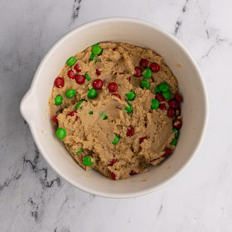 Christmas cookie dough in a mixing bowl with red and green M&M's.