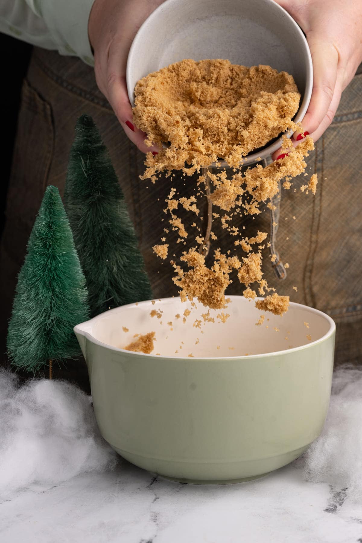 Adding light brown sugar to a mixing bowl to cream with unsalted butter.