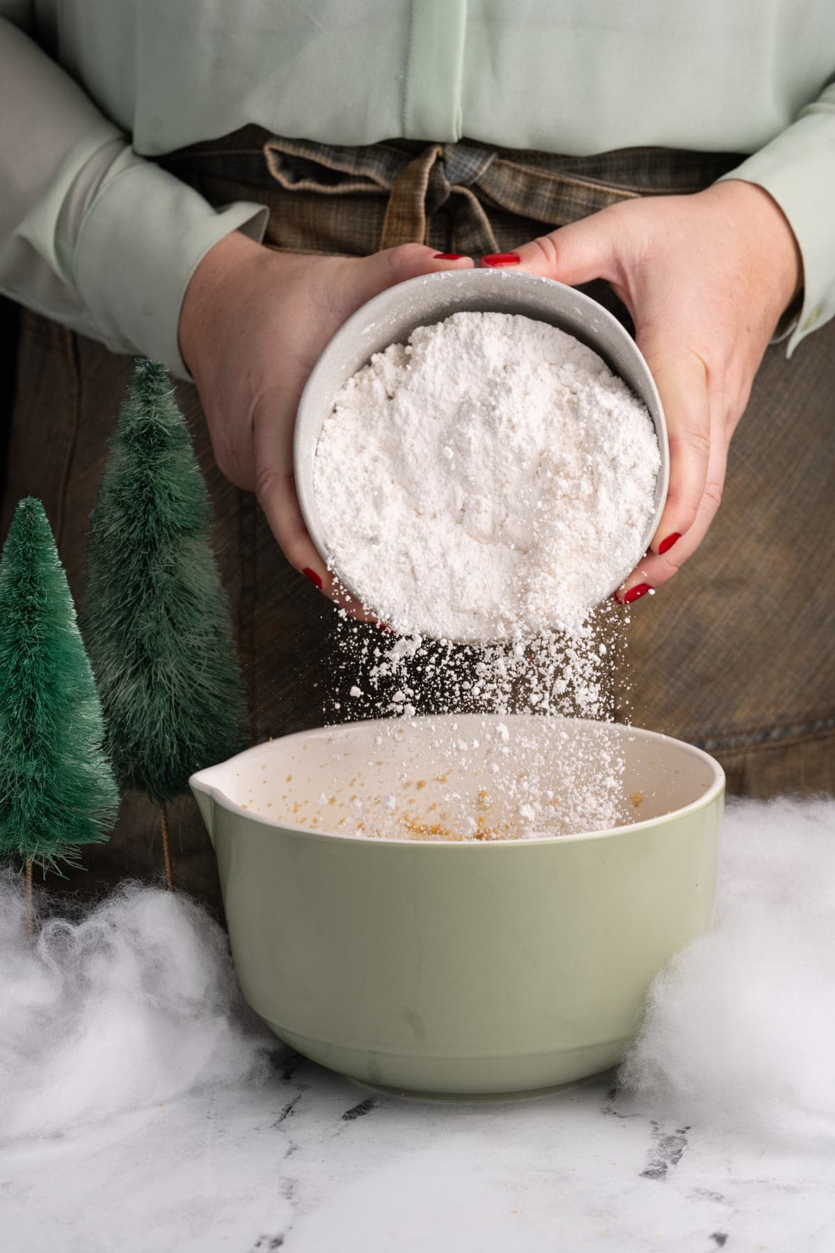 Adding flour along with other dry ingredients to M&M Christmas cookie dough.