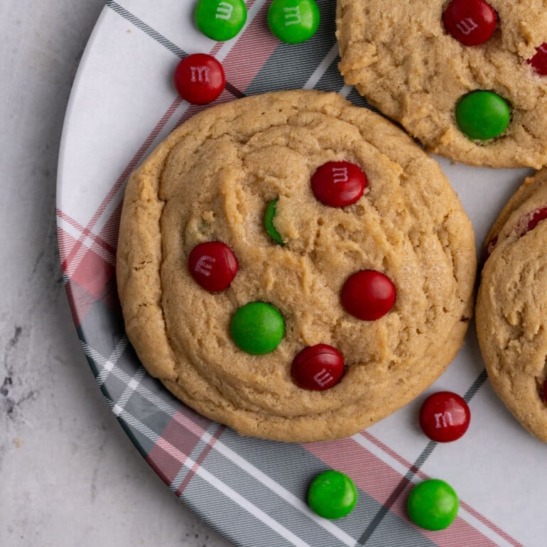 Christmas themed plate with green and red M&M Christmas cookies on it.