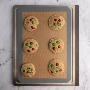 Still hot, fresh out of the oven Christmas cookies lined up on a baking sheet.