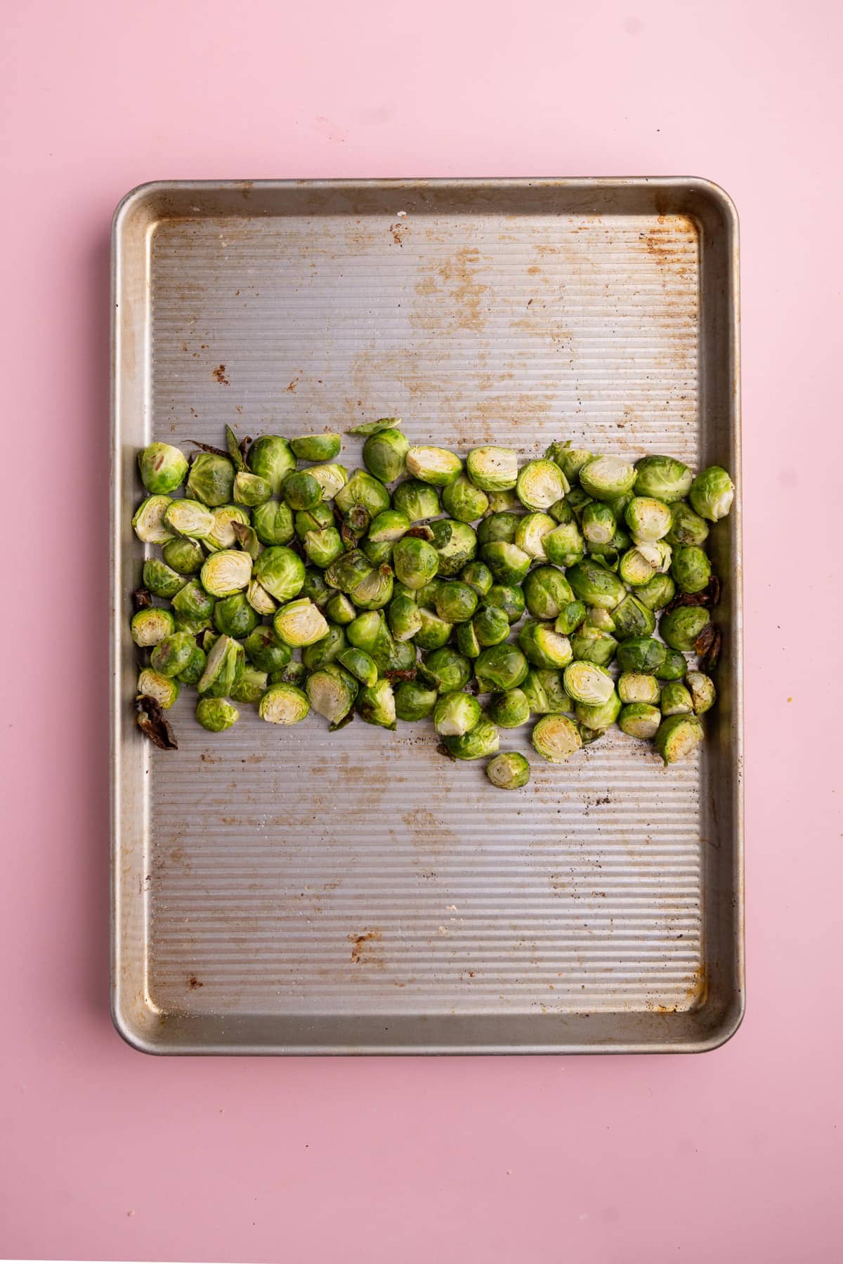 Roasted brussels sprouts pushed to the center of a baking tray to add Parmesan crust.