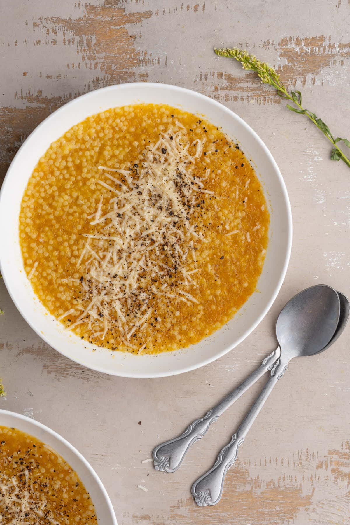 Close up of Pastina soup finished with Parmigiano reggiano and fresh cracked black pepper. 