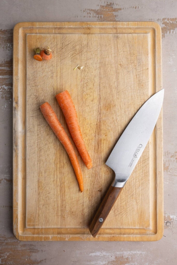 Cutting the ends off of carrots to prep them for vegetable-based soup.