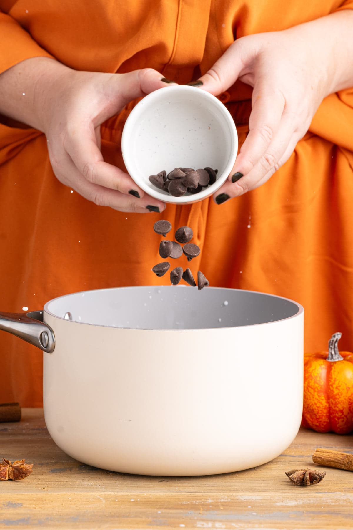Adding chocolate chips to a pot with milk to melt and combine