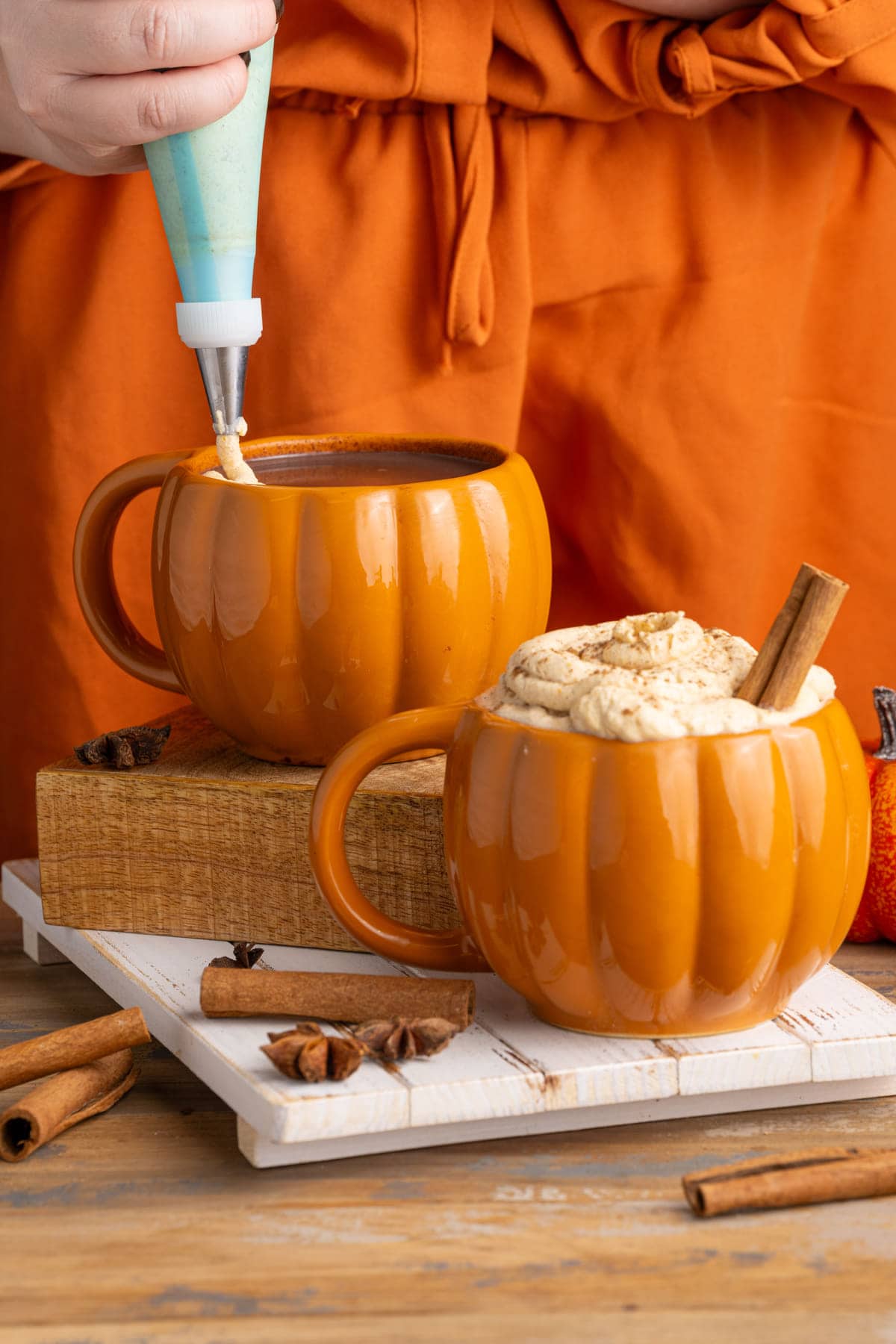 Adding pumpkin spice whipped cream to hot chocolate with pumpkin
