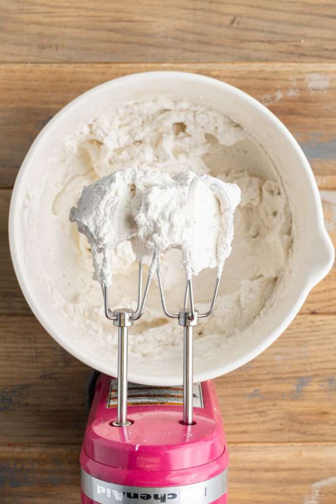 Homemade whipped cream on the whisk attachments of a hand mixer