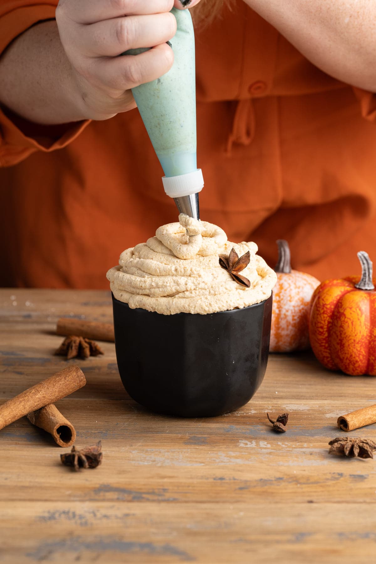 Adding pumpkin whipped cream to a bowl using a piping bag