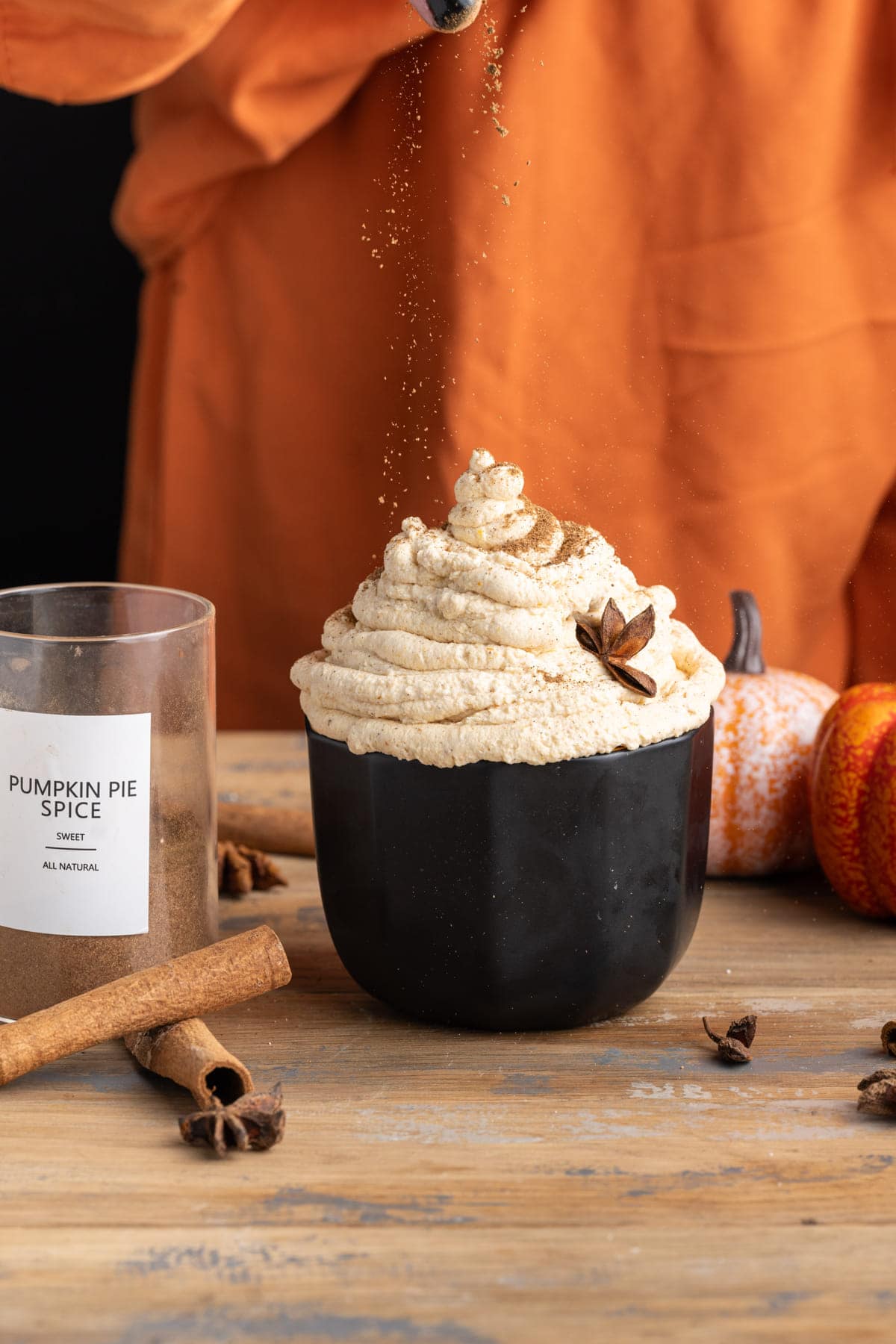 Sprinkling extra pumpkin pie spice over pumpkin whipped cream