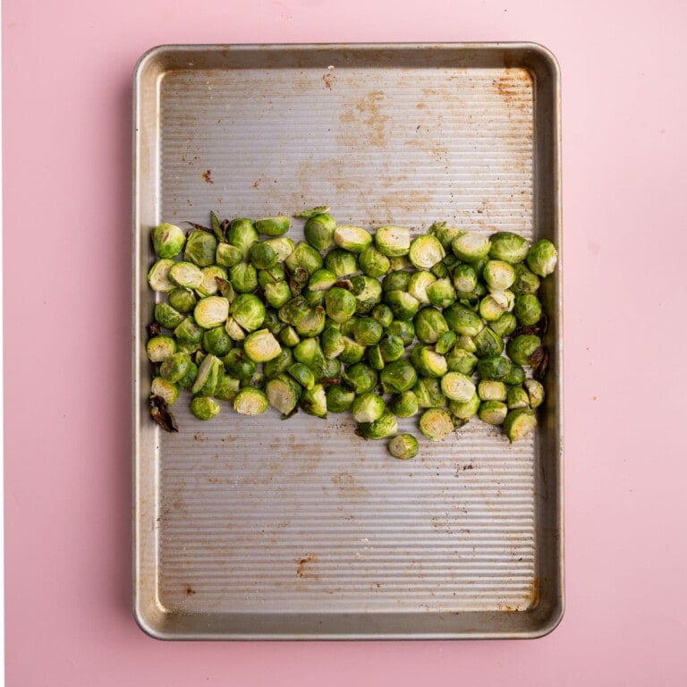 Roasted brussels sprouts pushed to the center of a baking tray to add Parmesan crust.
