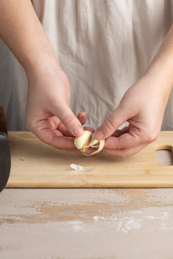 Peeling outermost paper-thin layer away from the garlic