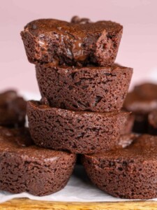 A stack of bite-sized brownie rounds with the top one having a bite taken out of it.