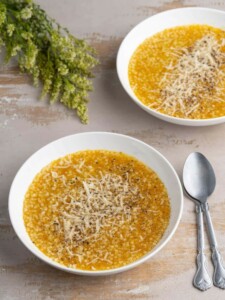 Two bowl of veggie-packed pastina soup garnished with Parmigiano reggiano.