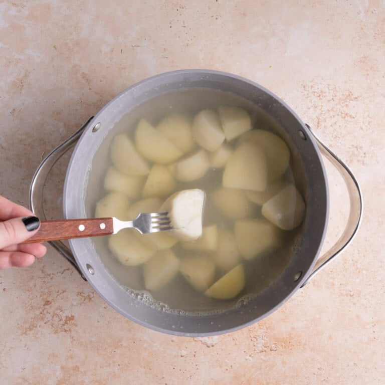 Poking boiled potato with a fork to check if it's tender.