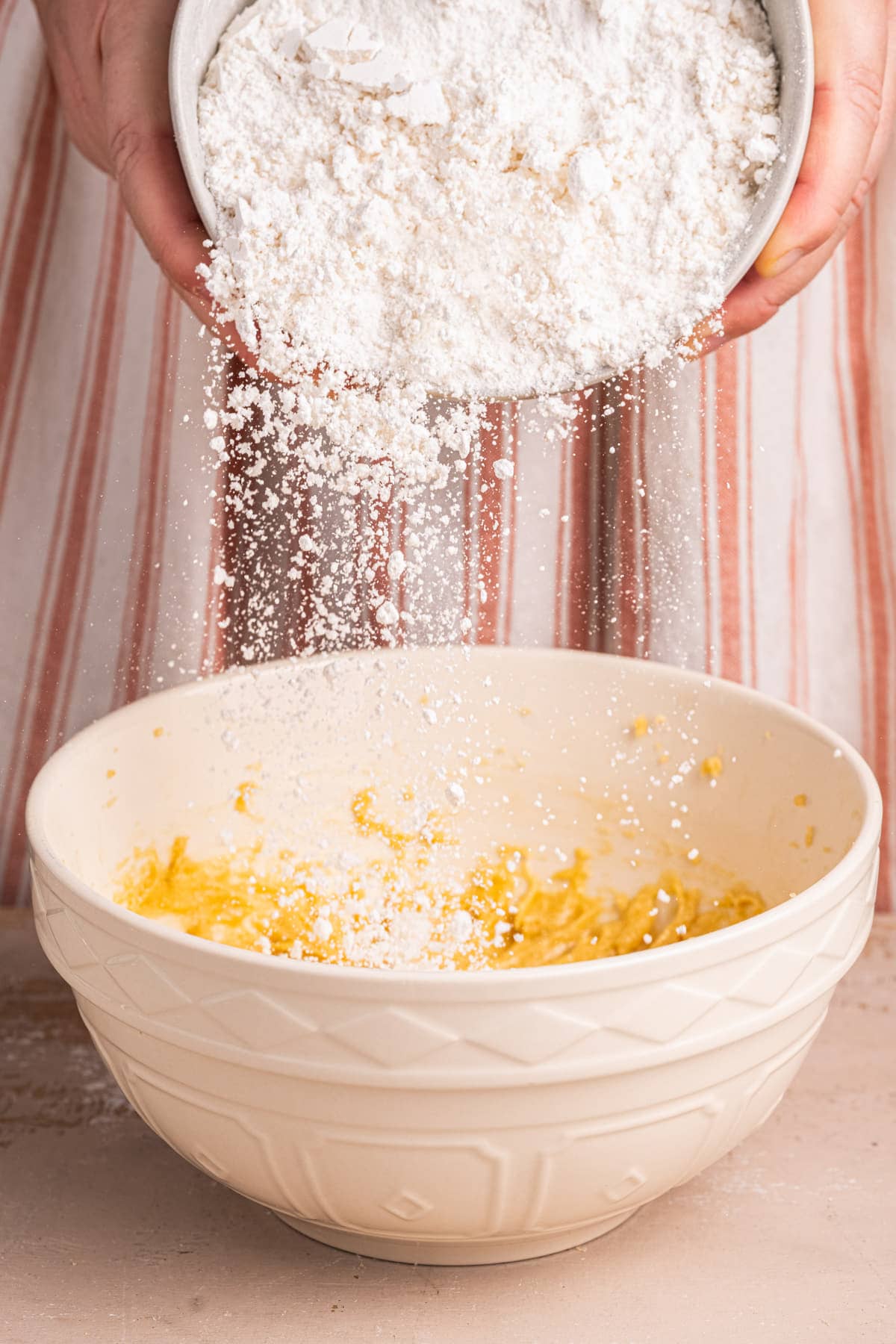 Adding all-purpose flour to a large mixing bowl to make cookie dough.