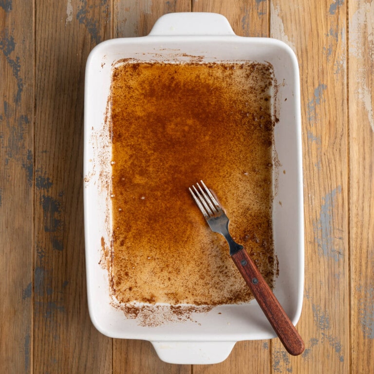 Apple cider mixed with cinnamon and brown sugar in a baking dish.