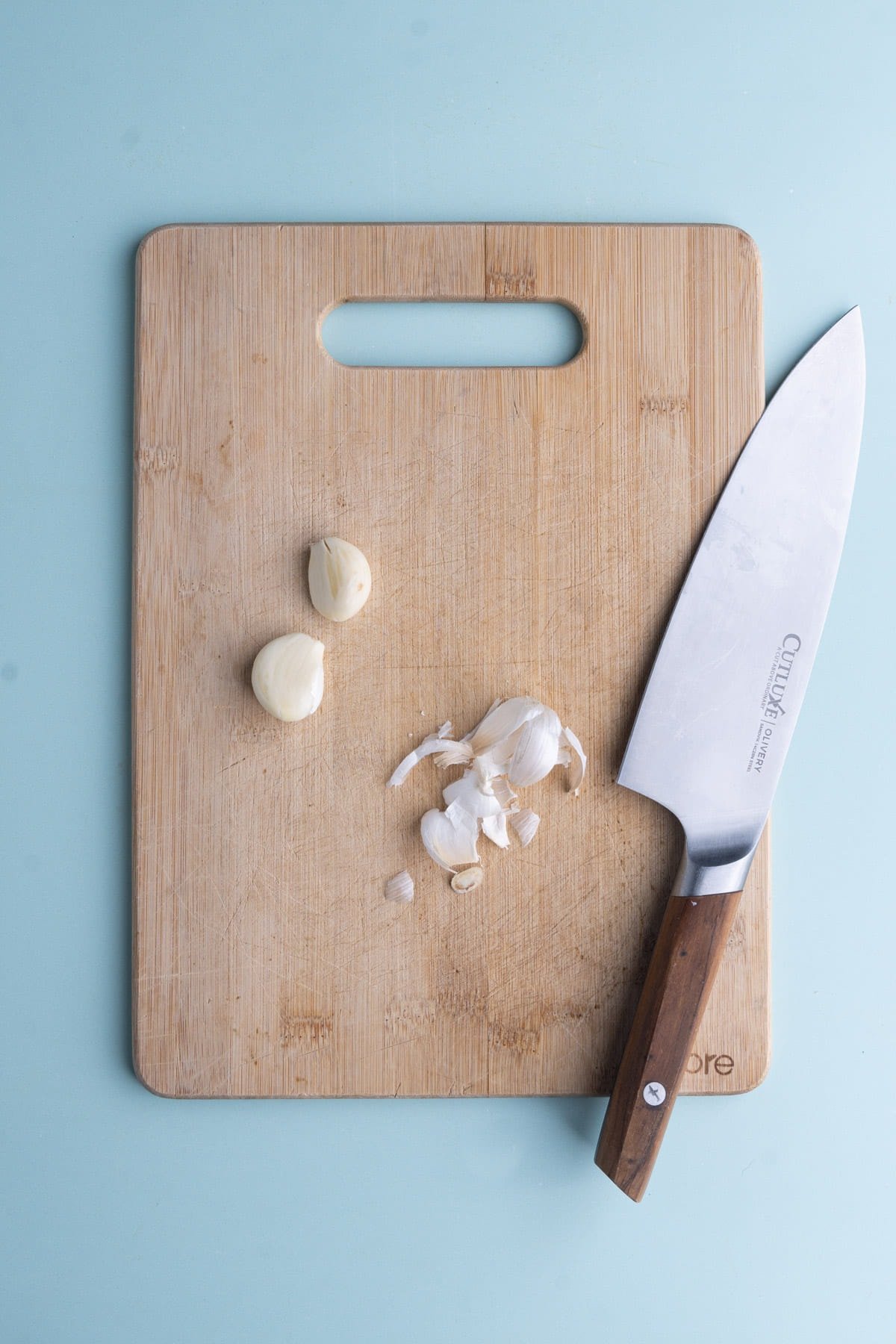 Peeled garlic on a cutting board ready to add to a food processor. 