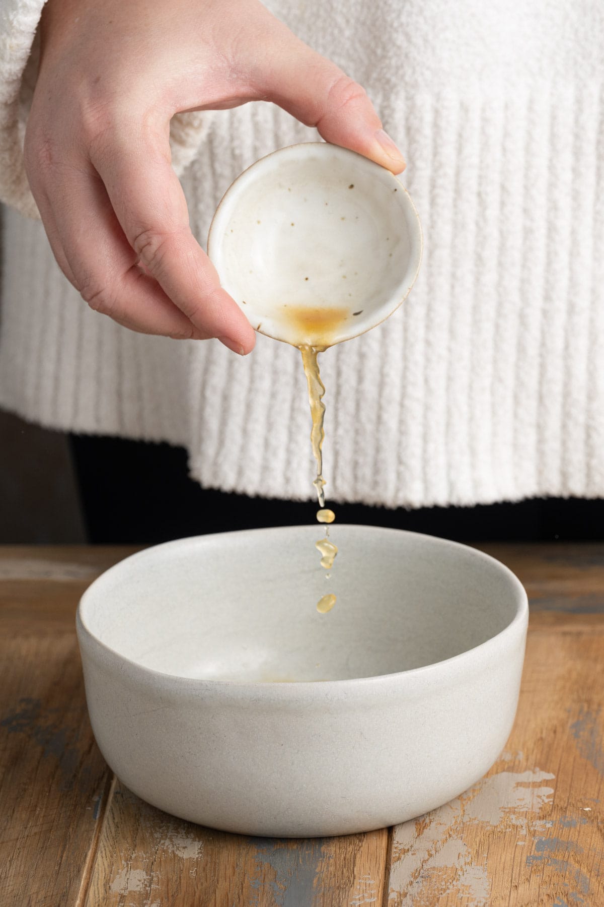 Adding apple cider to a bowl to mix up a cinnamon sugar sauce for sauteed apples. 