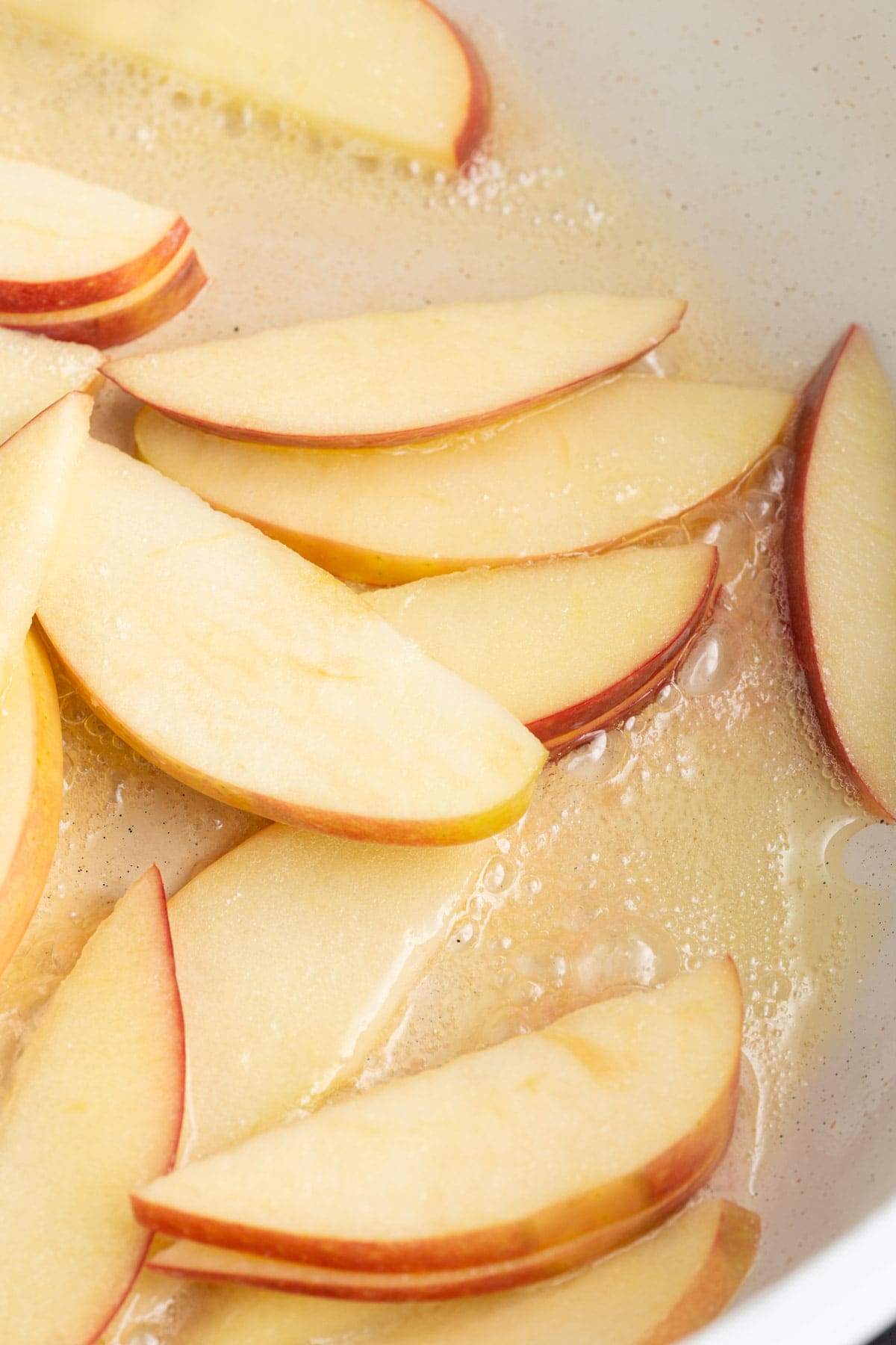 Apples cooking in a pan with sizzling butter. 