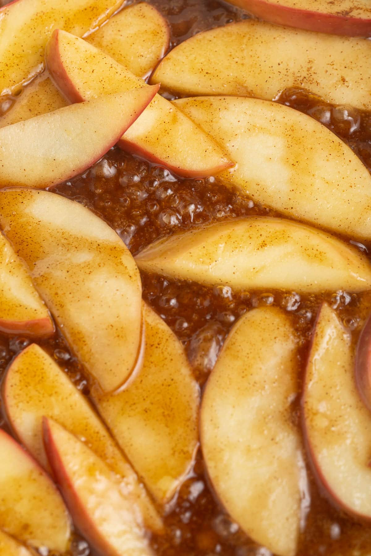 Sliced apple cooking in cinnamon sugar sauce.