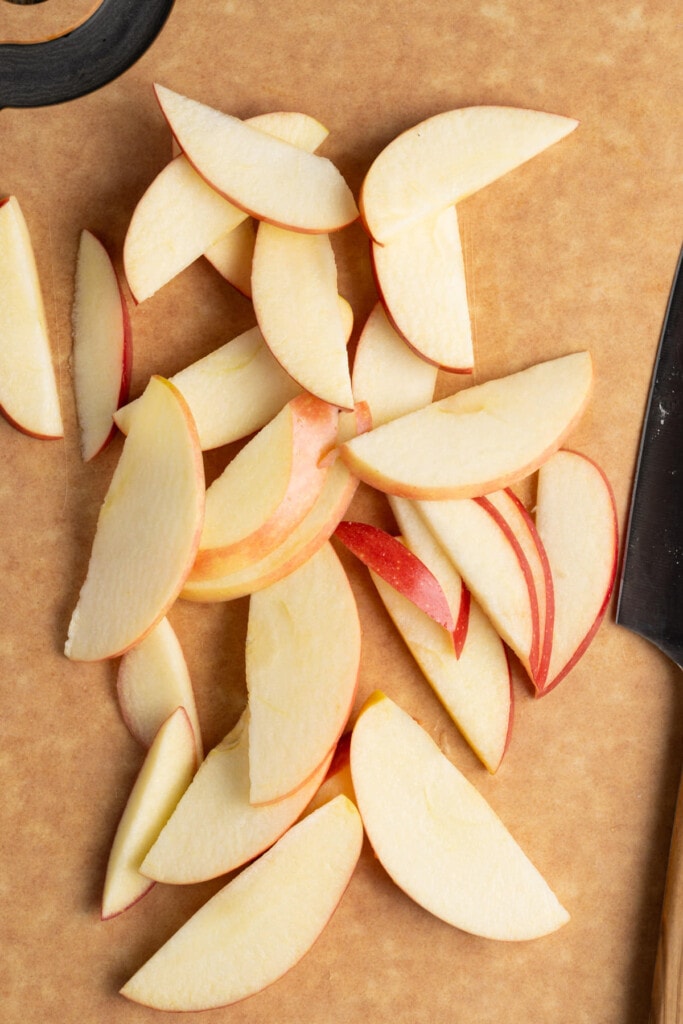 Cored and thinly sliced apple on a cutting board.