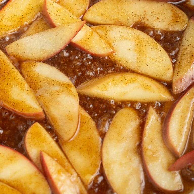 Cooking apples in cinnamon, sugar, and butter in a frying pan.