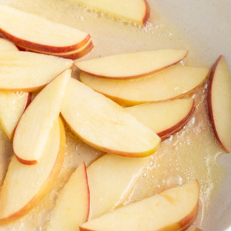 Cooking sliced apples in butter on the stovetop.