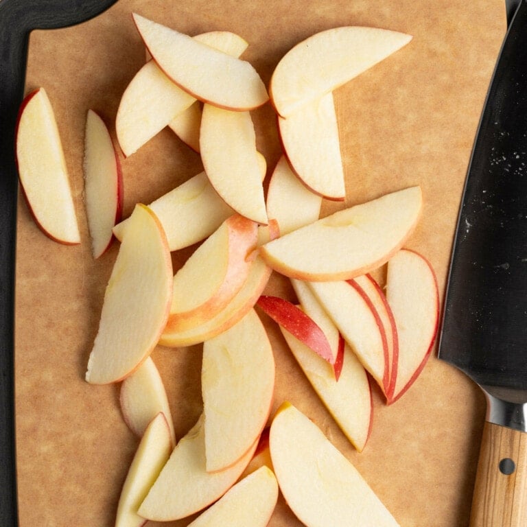Apple sliced thin on a cutting board.