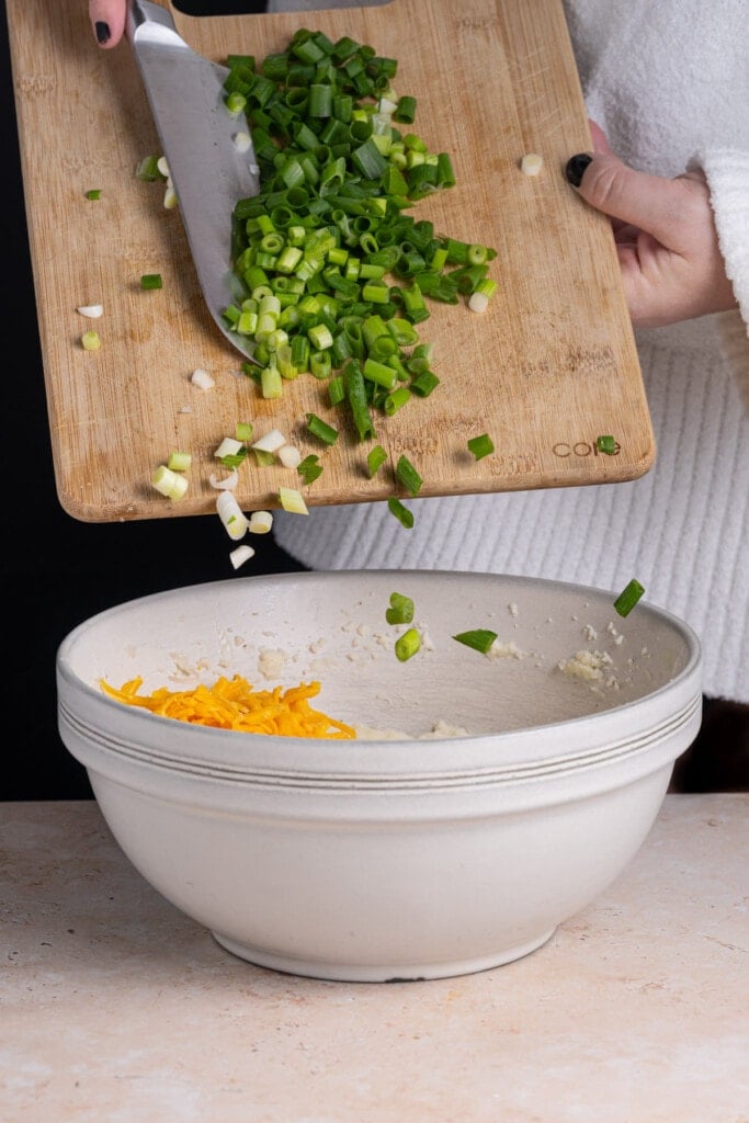 Adding scallions to cheesy mashed potatoes.