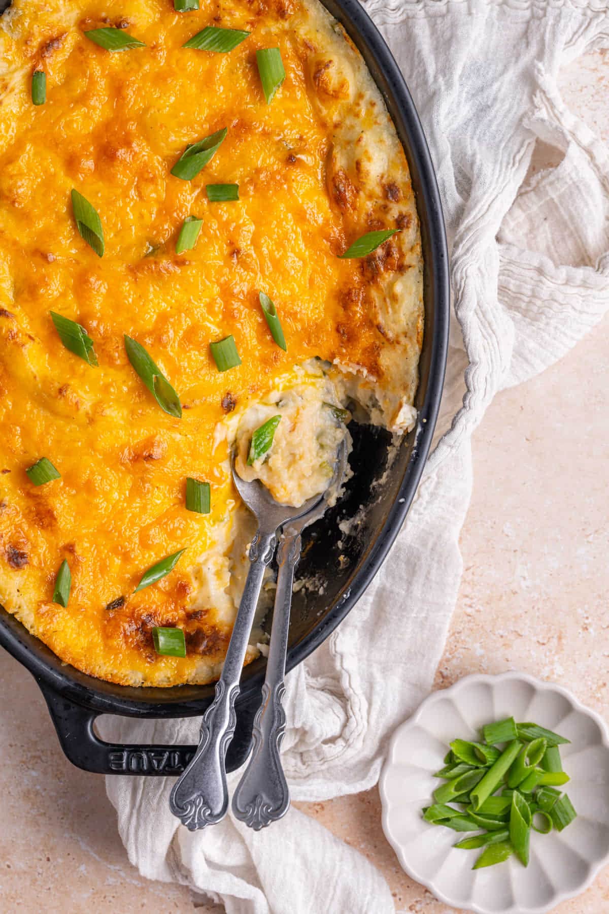 Cheesy Twice-Baked Mashed Potato Casserole with two serving spoons. 