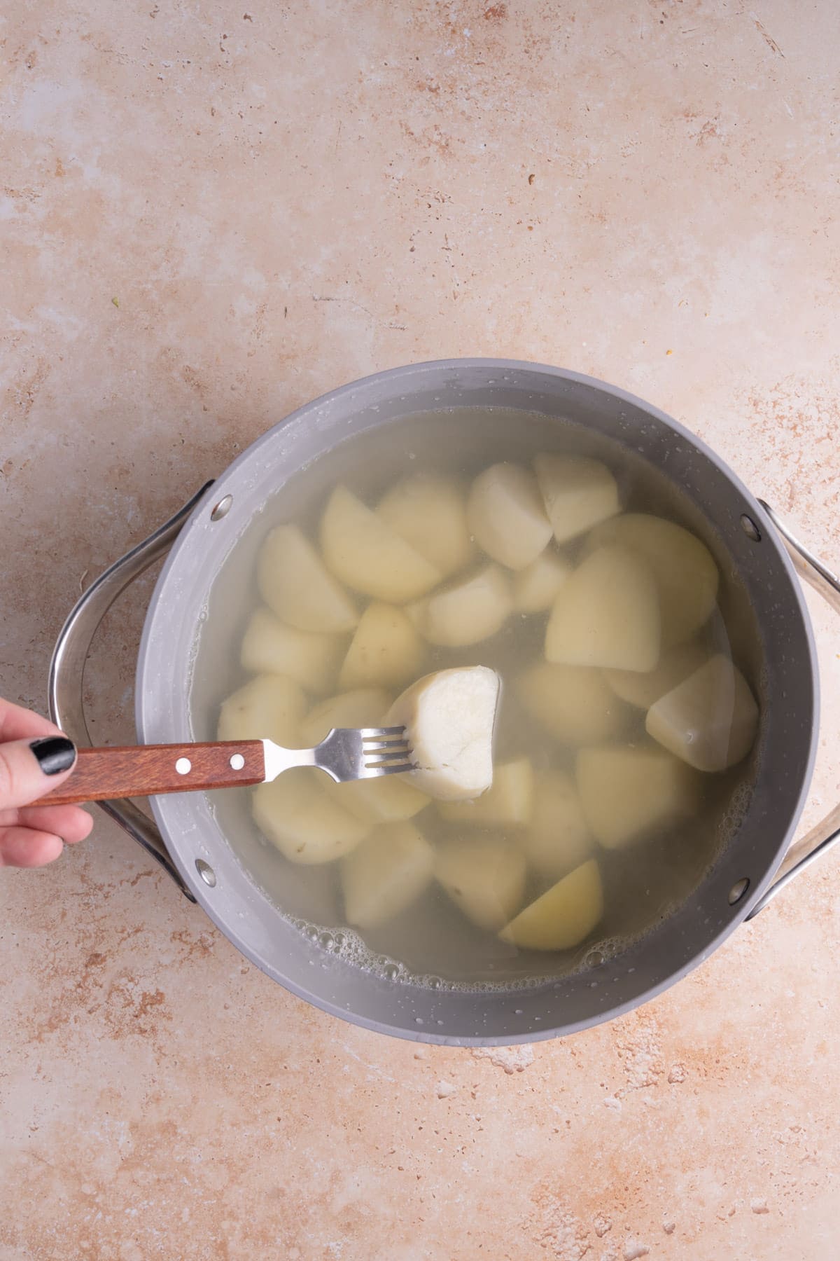 Using a fork to test if boiled potatoes are cooked. 