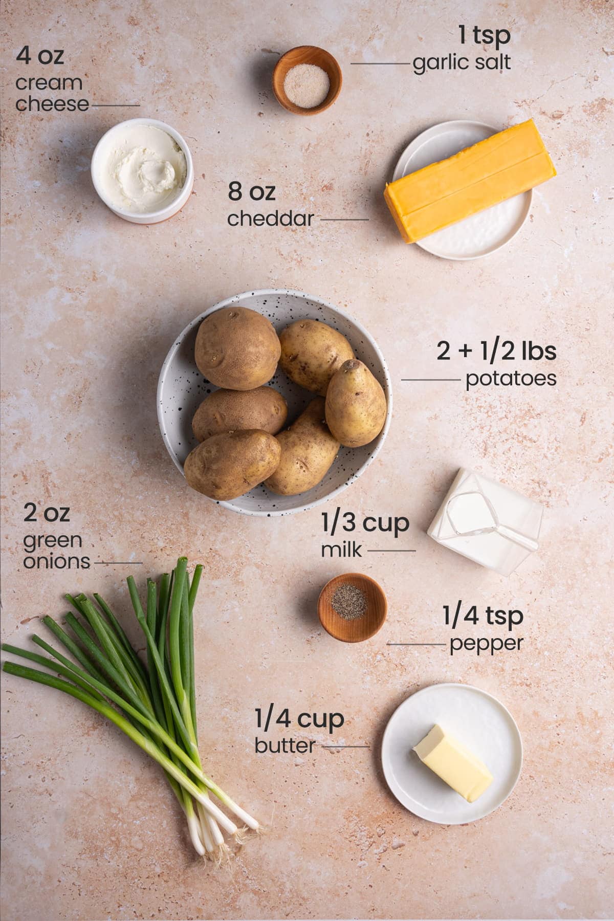 ingredients for twice-baked mashed potatoes - garlic salt, cream cheese, cheddar, potatoes, green onions, milk, pepper, butter