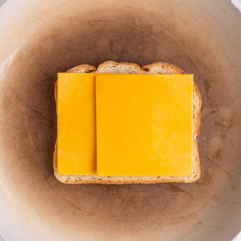Cheddar cheese layered on buttered bread frying in a hot pan.