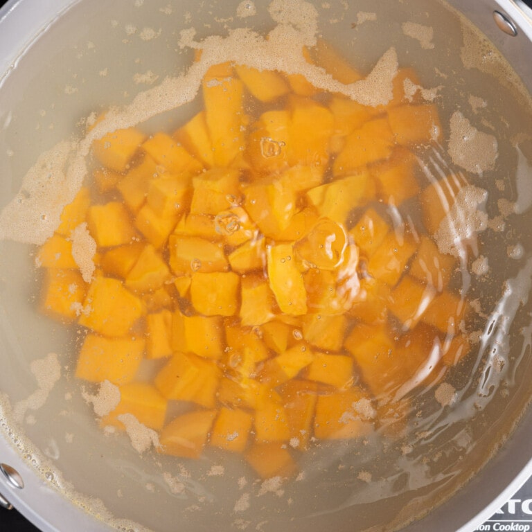 Peeled and cubed sweet potato boiling in water until tender.