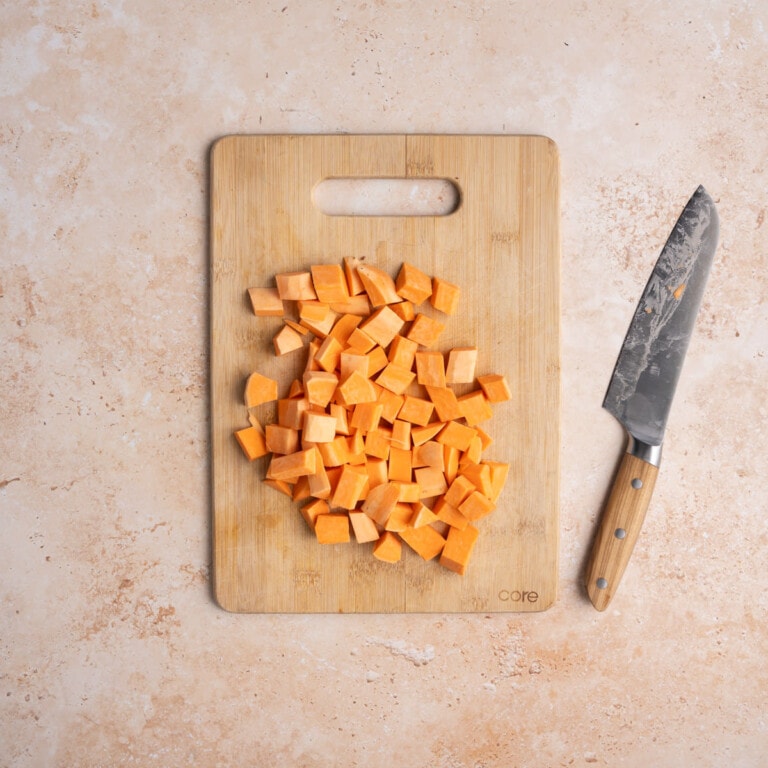 Cutting board with cubed sweet potato on it.