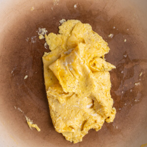 Scrambled eggs in the center of a frying pan, cooked and formed into roughly the shape of a slice of bread.
