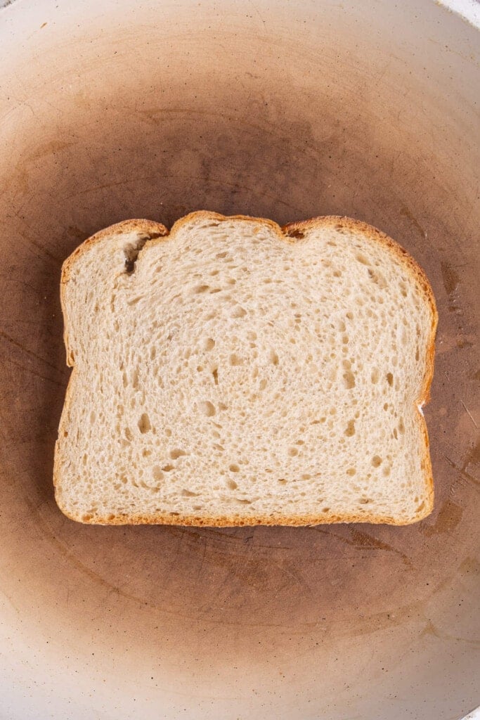 Buttered bread toasting in a pan with buttered side down. 