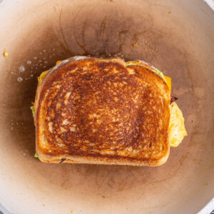 Epic egg and cheese breakfast sandwich frying in a pan.