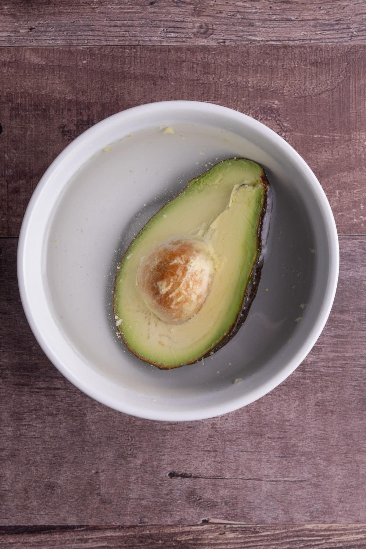 Covering half an avocado with water in a bowl to save it for later. 