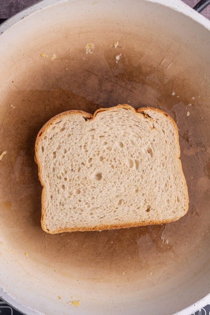 Placing a slice of buttered bread onto a hot frying pan to toast. 