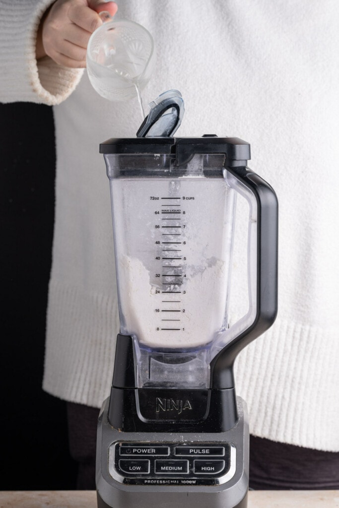 Adding cold water to pie crust with blender on.