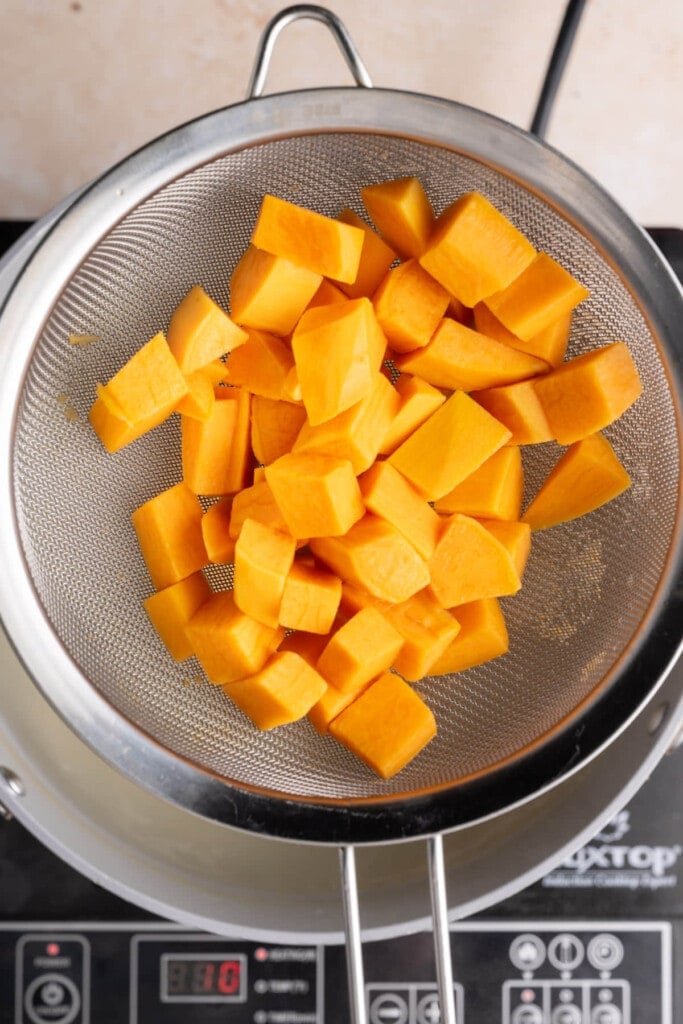 Straining sweet potato after boiling to dry it before making a pie filling out of it.