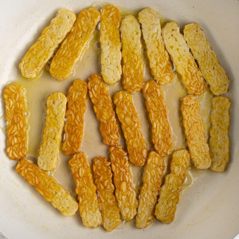 Frying tempeh in olive oil until both sides are golden brown.