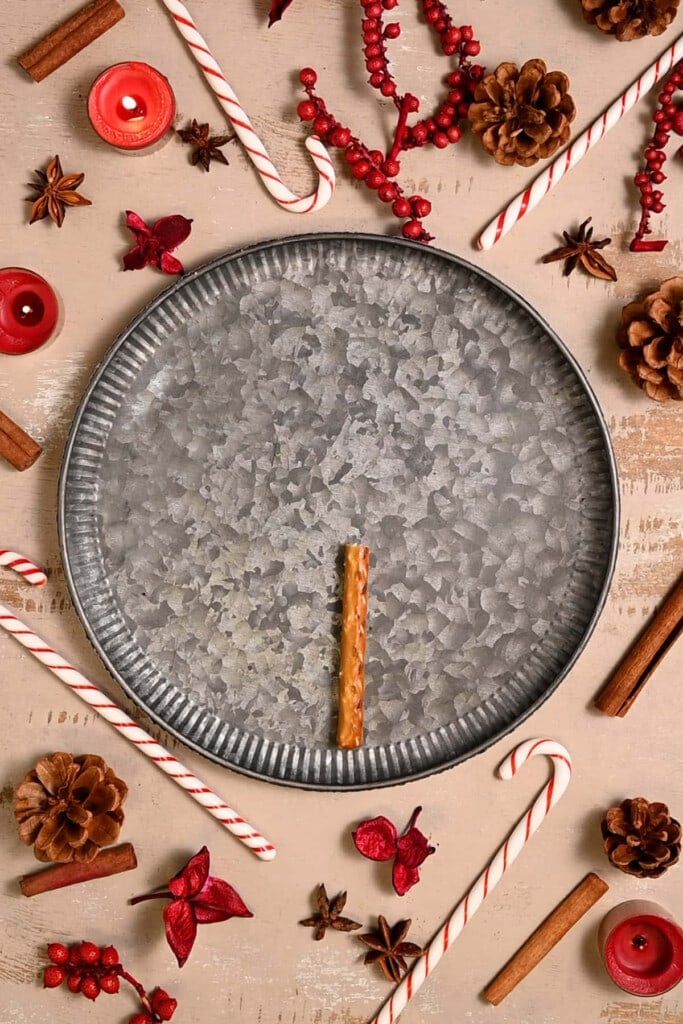 Adding a pretzel rod to a plate to resemble a Christmas tree trunk. 