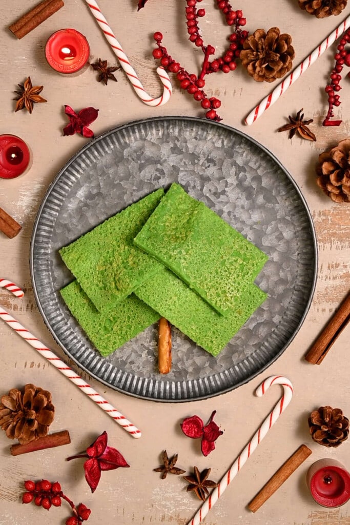 Layering more rectangular green pancakes on a plate to shape into a tree. 