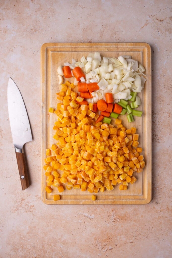 Roughly chopped celery, carrots, and onions, cubed butternut squash, and peeled garlic.