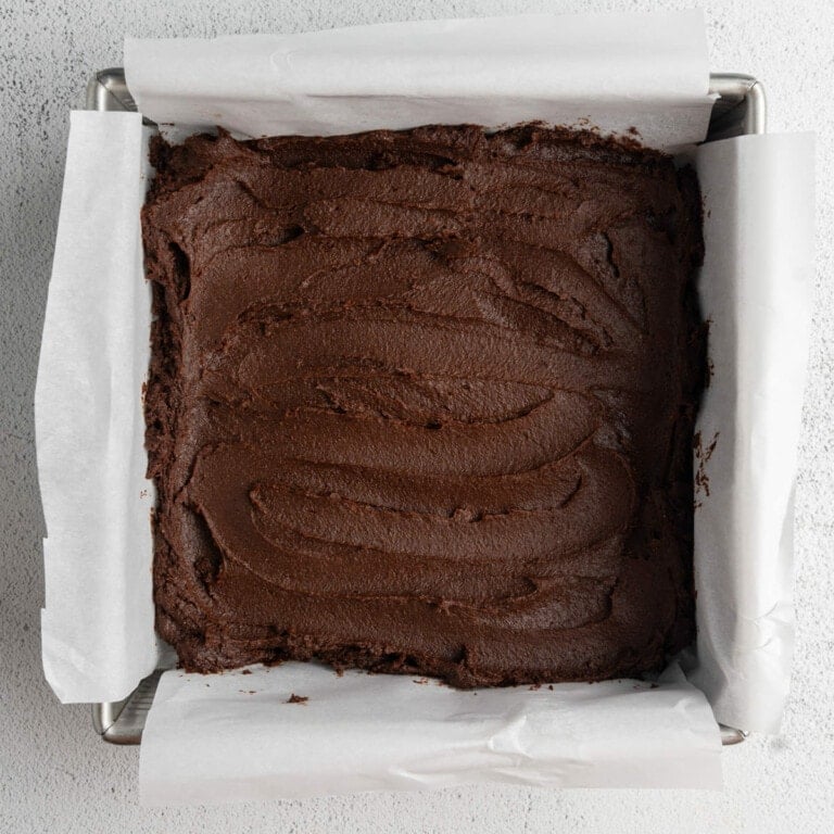 Thick brownie batter smoothed out in an 8x8-inch baking dish.
