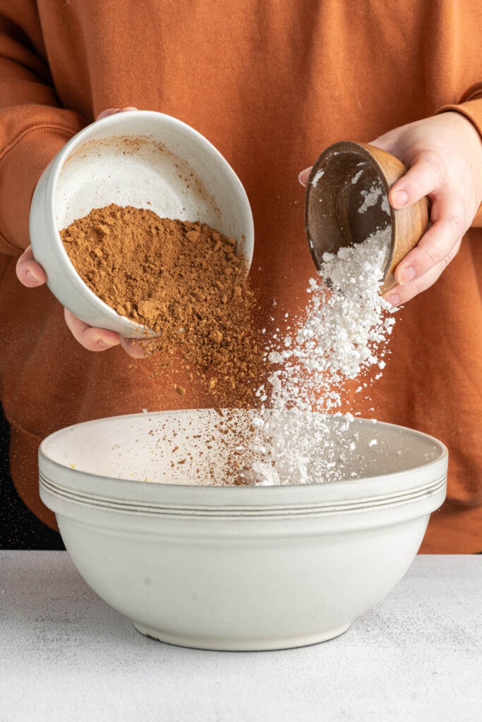 Adding cocoa powder and all-purpose flour to brownie batter base.