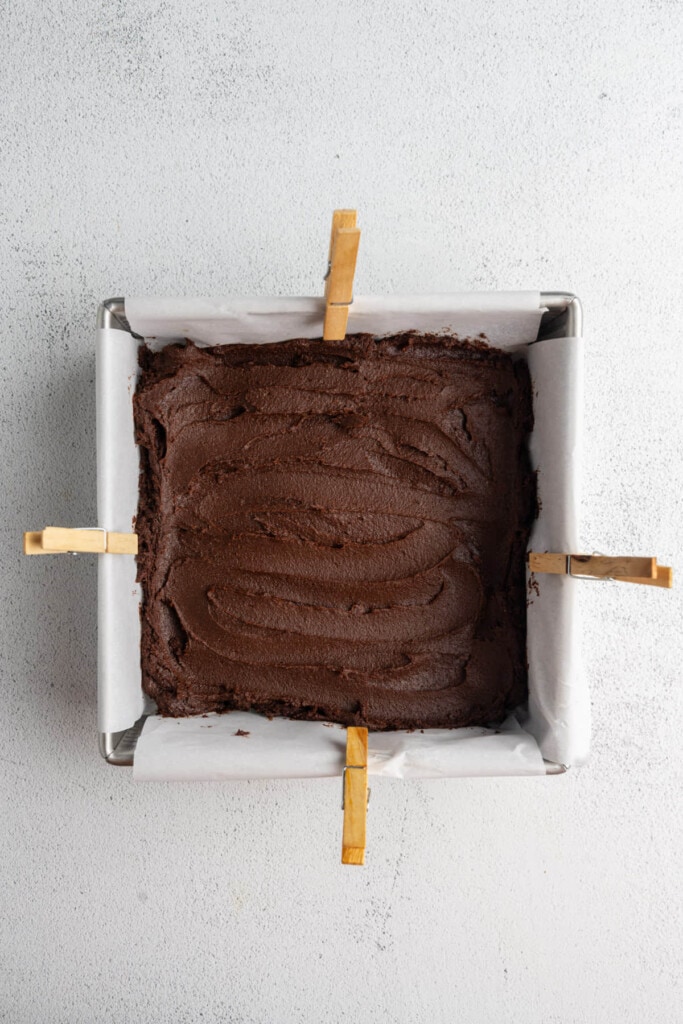 Smoothing brownie batter out in an even layer in a pan.
